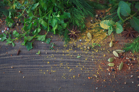 Mix of fresh herbs and spices assortment on wooden background.