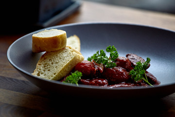 warm salad with chicken liver and grapes on the white plate. Warm salad from turkey liver. Warm salad with chicken liver in raspberry sauce.