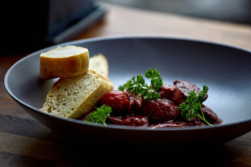 warm salad with chicken liver and grapes on the white plate. Warm salad from turkey liver. Warm salad with chicken liver in raspberry sauce.