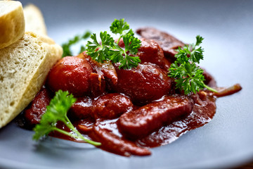 warm salad with chicken liver and grapes on the white plate. Warm salad from turkey liver. Warm salad with chicken liver in raspberry sauce.