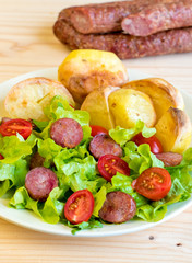 Smoked sausage with vegetables salad on a wooden board