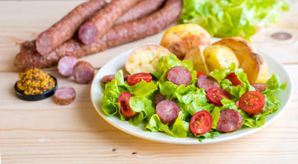 Smoked sausage with vegetables salad on a wooden board