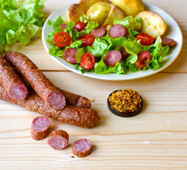 Smoked sausage with vegetables salad on a wooden board