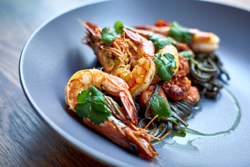 Cooked shrimps,prawns with seasonings on stone background. Fried shrimp with rosemary in a portioned frying pan on a dark table top view.  