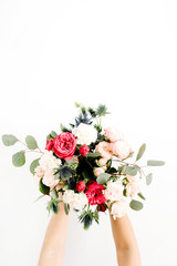 Girl's hands holding beautiful flowers bouquet: bombastic roses, blue eringium, eucalyptus, isolated on white background. Flat lay, top view. Floral composition