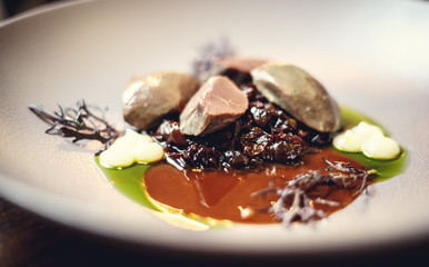 warm salad with chicken liver and grapes on the white plate. Warm salad from turkey liver. Warm salad with chicken liver in raspberry sauce.