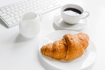 Business breakfast in office with keyboard, coffee and croissant on white table background