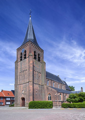 Fototapeta na wymiar Gothic Saint-Servatius church in Ravels, Belgium, against a blue sky with dramatic clouds.