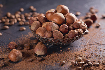 Hazelnut, coffee beans and cocoa powder in dark background.