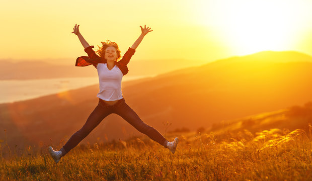 Happy woman jumping and enjoying life  at sunset in mountains