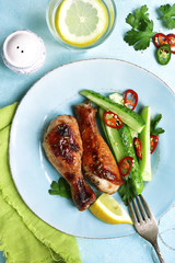 Roasted chicken drumctick with spicy cucumber salad.Top view.