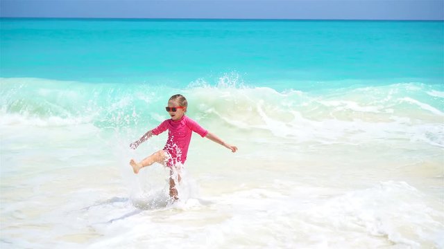 Adorable little girl at beach having a lot of fun in water