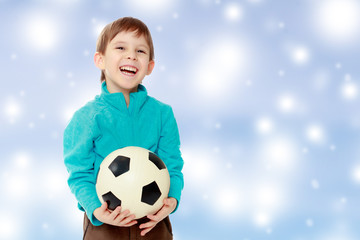 Little boy holds soccer ball.