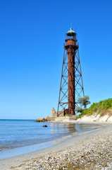 Fototapeta na wymiar Old lighthouse on the beach near the sea. Lighthouse on the coast of the island Dzharylgach.