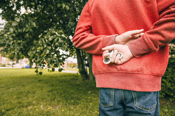boy hides behind his back a fidget spinner. child's hand squeeze toy spinner. Close up. Copy space...