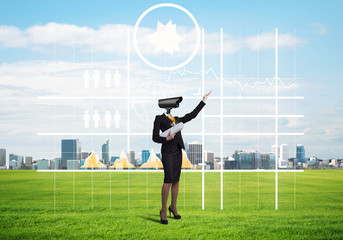 Camera headed woman standing on green grass against modern cityscape