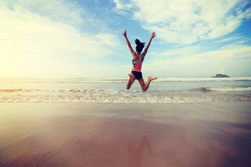 Fototapeta na wymiar young fitness woman wear swimsuit jumping on beach
