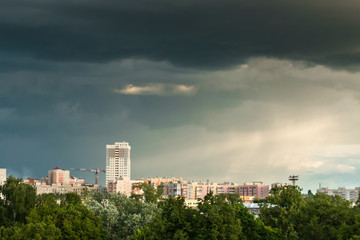 Fototapeta premium Cityscape with gloomy sky, rays of sun and rain.
