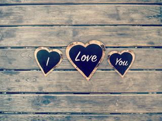 I love you on heart shape on chalkboard and wooden wall, vintage filtered