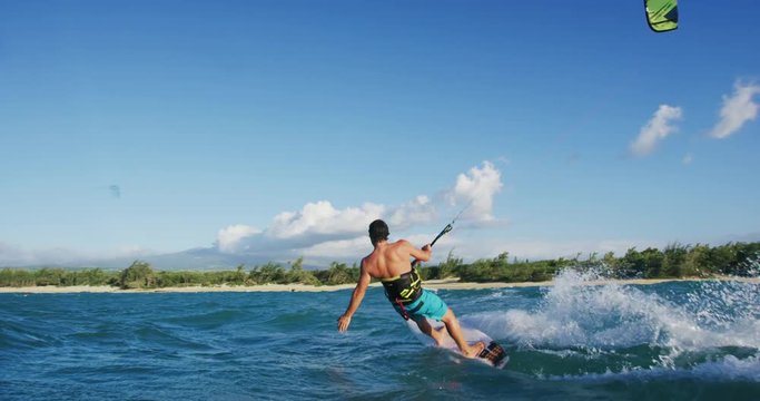 Young man kitesurfing on surfboard in blue ocean at sunet