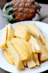 Cutting fresh pineapple and pineapple shelled Asian-style in white dish on the old wooden background. Tropical fruit concept.