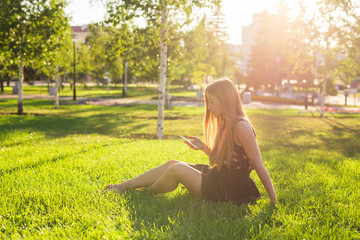 Girl listening to music streaming with headphones in summer on a meadow.