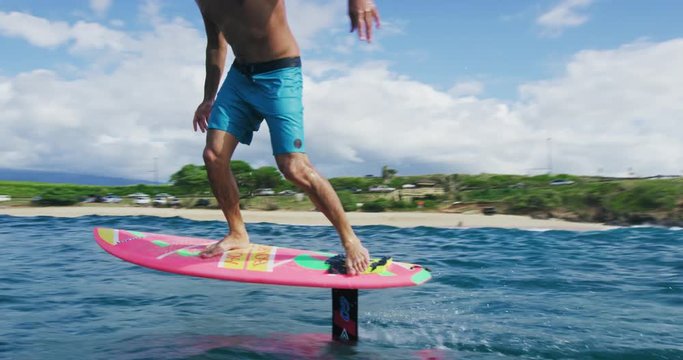 Surfer on hydrofoil surfboard riding blue ocean wave. Futuristic surfing on hoverboard