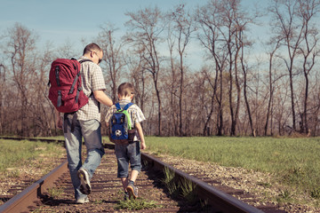Father and son walking on the railway at the day time.