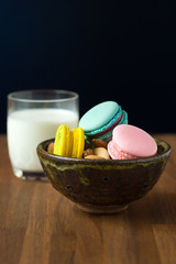 Tasty macaroons and cup of milk with almond on wooden background
