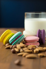 Fototapeta na wymiar Tasty macaroons and cup of milk with almond on wooden background