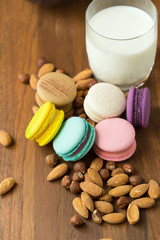 Tasty macaroons and cup of milk with almond on wooden background