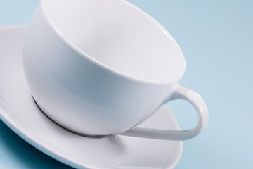 White cup and saucer on light blue background.