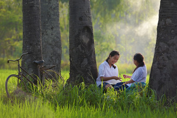 Schoolchildren painting something exercise books outdoor at summer