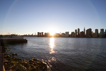 Fototapeta premium Sunset behind Manhattan reflects on East river