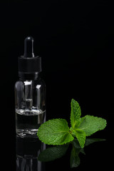 Liquid with a scent of green mint in a bottle on a black background