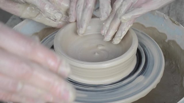 Master class on modeling of clay. Master potter teaches a child to make a clay pitcher