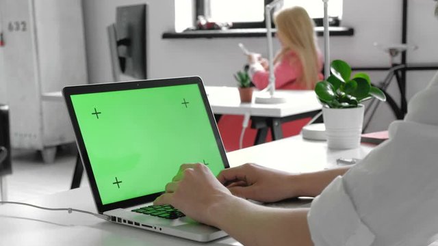 Tracking Shot of a Man Typing On A Laptop With A Chroma-key Green Screen 20s 4k