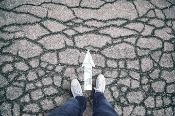 Concept business person standing on the cracked asphalt ground at straight arrow sign. Conceptual...