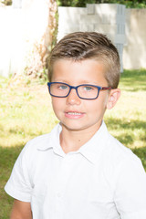 cute young blond boy in the family garden with glasses