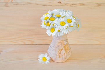 A bouquet of daisies in a vase on a wooden background