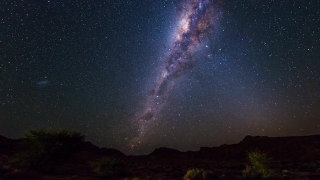The apparent rotation of an outstandingly bright Milky Way and starry sky beyond the mountains of the Namib desert, Namibia. Time Lapse.
