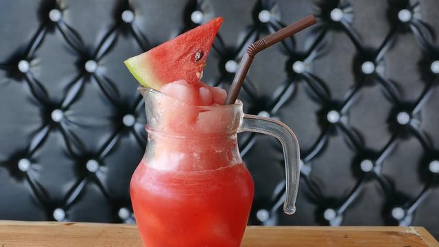 Zoom in of watermelon juice on wooden table in cafe.