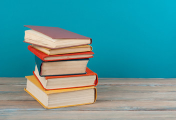 Book stacking. Open hardback books on wooden table and beige background. Back to school. Copy space for ad text.