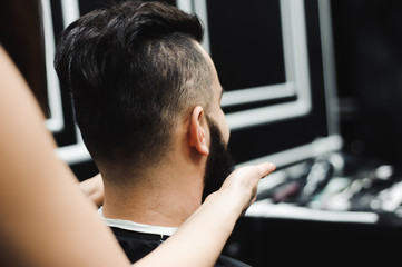Master cuts hair and beard of men in the barbershop, hairdresser makes hairstyle for a young man