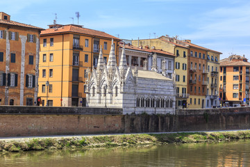 Fototapeta na wymiar Pisa - historic townhouses along the Arno embankment. Small Gothic church of Santa Maria della Spina from 1230