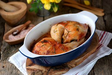Chicken legs baked with fresh rosemary and pepper on an old wooden background. Rustic style.