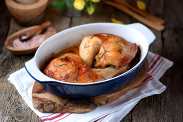 Chicken legs baked with fresh rosemary and pepper on an old wooden background. Rustic style.