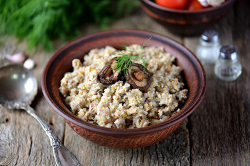 Buckwheat with chicken and mushrooms on an old wooden background. Rustic style.