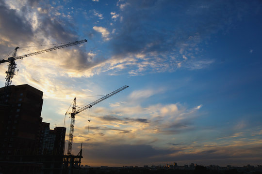 2 tower cranes on a blue sky background