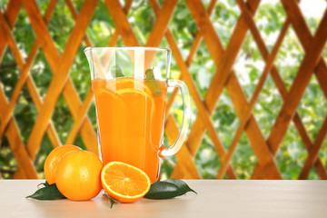 Glass jug of orange lemonade on blurred background